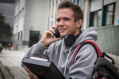 Üniversitenin önünde kulaklıklı bir üniversite öğrencisi.