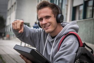 Üniversitenin önünde kulaklıklı genç bir öğrenci.