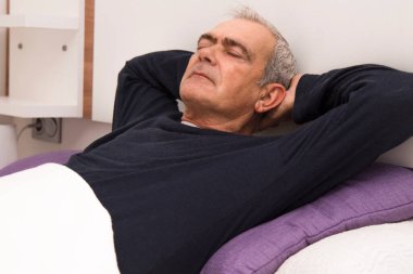 Rahatlamış bir adam yatakta yatıyor.