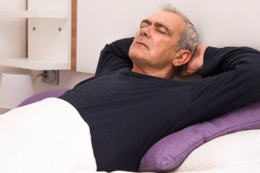 Rahatlamış bir adam yatakta yatıyor.