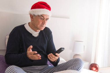 Noel Baba şapkası ve uzaktan kumandalı şaşırmış bir adam.