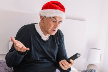 Noel Baba şapkası ve uzaktan kumandalı şaşırmış bir adam.