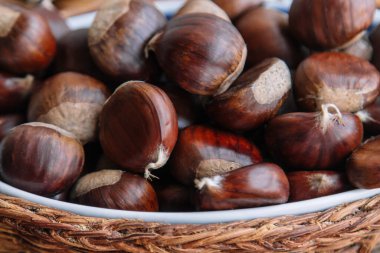 Tahta arka planda bir sepet dolusu taze kestane