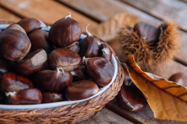 Tahta arka planda bir sepet dolusu taze kestane