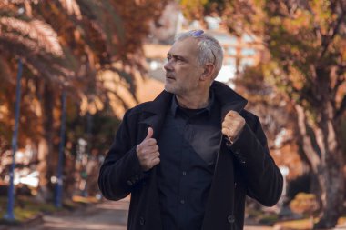 Sonbahar manzarasında ceketli ve güneş gözlüklü bir adam.