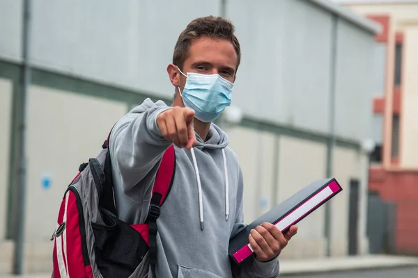 teenage student with medical mask pointing a direction