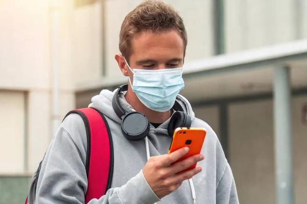 student with medical mask and mobile phone