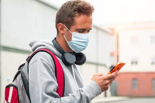 student with medical mask and mobile phone