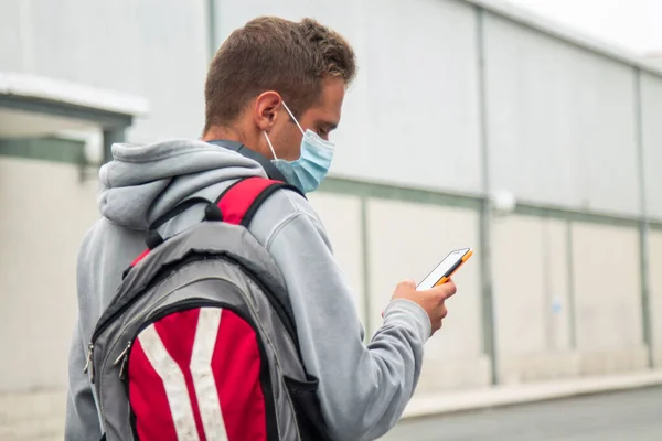 student with medical mask and mobile phone