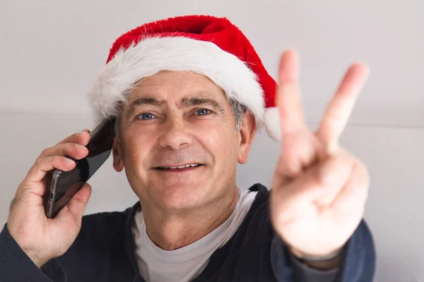 Attraktiver Reifer Mann Mit Weihnachtsmann Hut Und Handy Der Siegeszeichen — Stockfoto