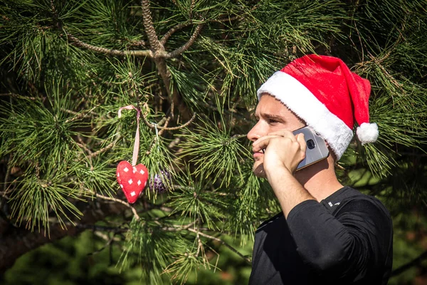 Νεαρός Άνδρας Καπέλο Santa Χριστούγεννα Κινητό Του Τηλέφωνο Και Χριστουγεννιάτικο — Φωτογραφία Αρχείου