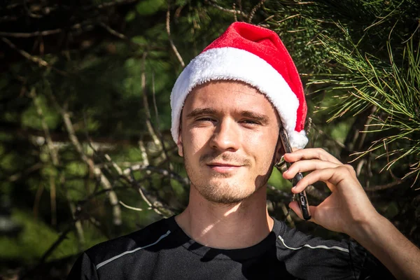 Junger Mann Mit Weihnachtsmütze Handy Und Weihnachtsbaum — Stockfoto