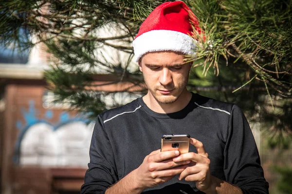 Junger Mann Mit Weihnachtsmütze Nutzt Smartphone — Stockfoto