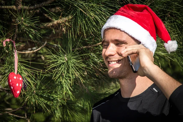 Νεαρός Άνδρας Καπέλο Santa Χριστούγεννα Κινητό Του Τηλέφωνο Και Χριστουγεννιάτικο — Φωτογραφία Αρχείου
