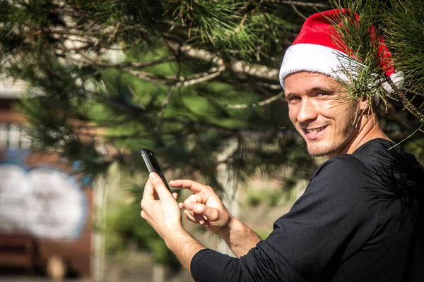 Νεαρός Άνδρας Καπέλο Santa Χριστούγεννα Χρησιμοποιώντας Smartphone — Φωτογραφία Αρχείου