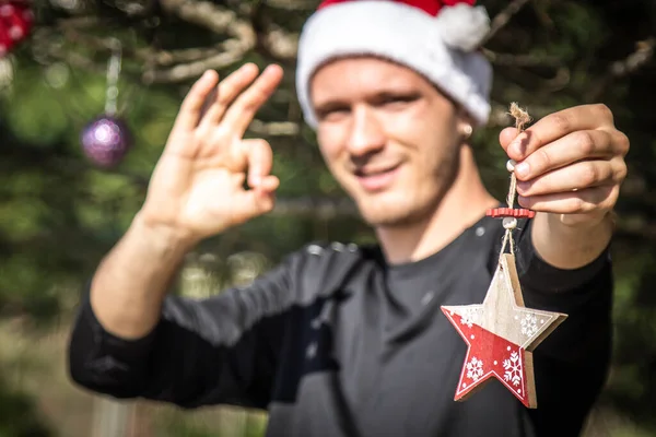 Junger Mann Mit Weihnachtsmann Mütze Der Weihnachtsschmuck Weihnachtsbaum Platziert — Stockfoto