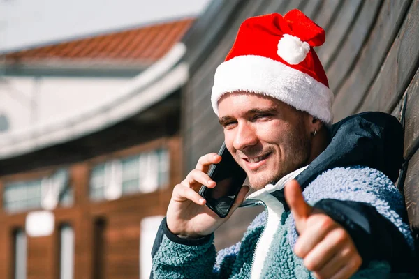 Άντρας Χριστουγεννιάτικο Καπέλο Μιλάει Στο Τηλέφωνο Και Κάνει Μια Καλή — Φωτογραφία Αρχείου