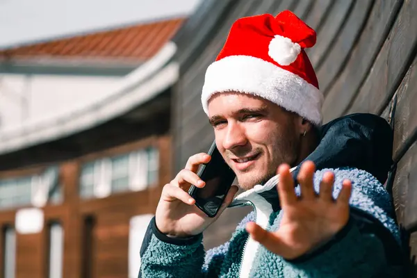 Mann Mit Weihnachtsmannmütze Und Handy Winkt Und Gratuliert Weihnachten — Stockfoto