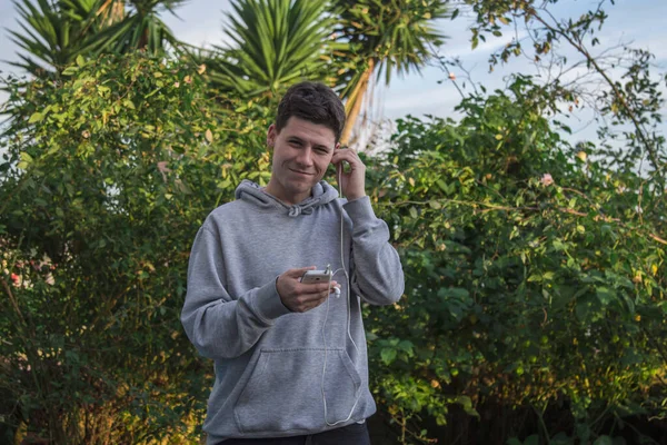 Νεαρός Άνδρας Φούτερ Χρησιμοποιώντας Κινητό Τηλέφωνο Και Ακουστικά — Φωτογραφία Αρχείου