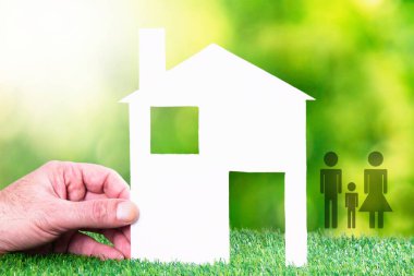 hand with paper house, father, mother, son. concept of house and family