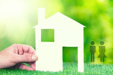 hand with paper house and couple. concept of house and family