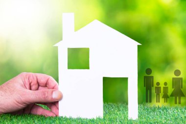 hand holding paper house and family. concept of house and family