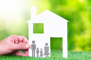 hand holding paper house and family. concept of house and family