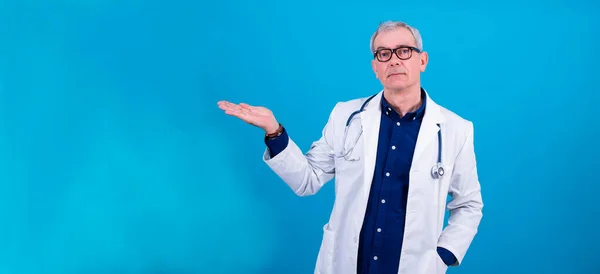 Arzt Zeigt Mit Dem Finger Auf Blauen Hintergrund — Stockfoto