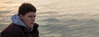 Arkada okyanus olan yalnız ve üzgün bir adam.