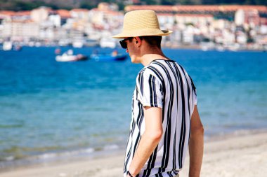 Genç adam sahilde yürüyor.