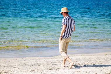 Genç adam sahilde yürüyor.