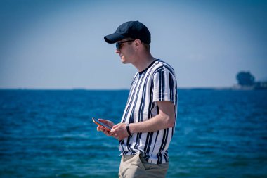 Sahilde cep telefonu kullanan genç bir adam.