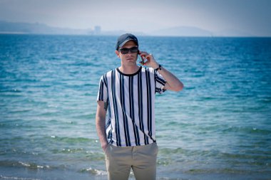 Kumsalda rahat bir adam cep telefonuyla konuşuyor.