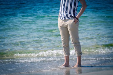 Kumsalda yürüyen rahat bir adam.