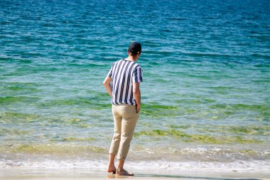 Kumsalda yürüyen rahat bir adam.