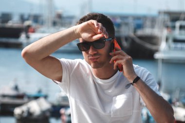 Marinada akıllı telefonlu yorgun ve terli genç bir adam.