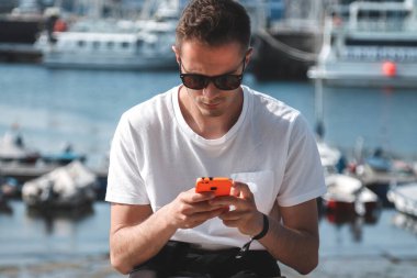 Marina 'da akıllı telefonu olan çekici bir genç adam.