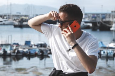 Marina 'da akıllı telefonu olan çekici bir genç adam.