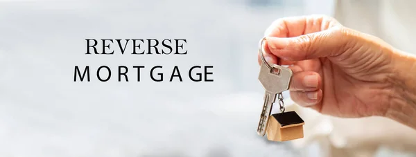 senior hand holding house key and keychain. investment and reverse mortgage concept