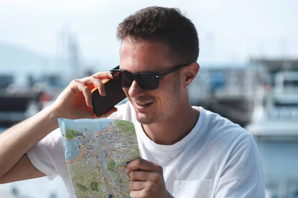 young tourist man consulting the map with the smartphone