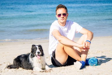 Sınırdaki köpeğiyle plajda rahat bir adam.