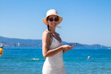 Plajda rahat bir kadın cep telefonu kullanıyor.