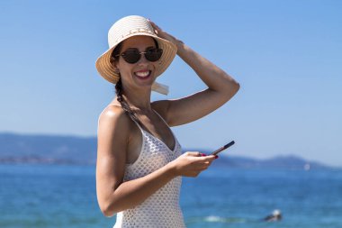 Plajda rahat bir kadın cep telefonu kullanıyor.