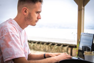 young man in outdoor bar using laptop