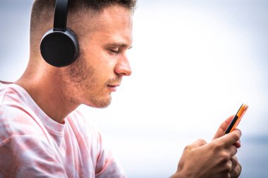 man using mobile phone and listening to music on the beach