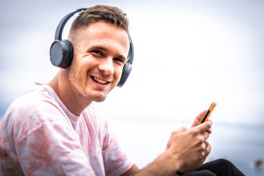 man using mobile phone and listening to music on the beach