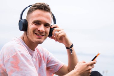 man using mobile phone and listening to music on the beach