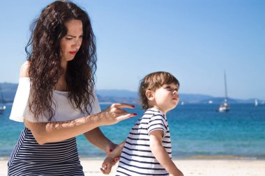 young mother applying sunscreen lotion on son 