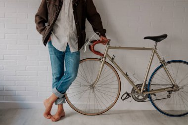 hipster with bicycle leaning against the wall in an attitude of waiting or resting