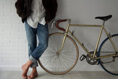 hipster with bicycle leaning against the wall in an attitude of waiting or resting